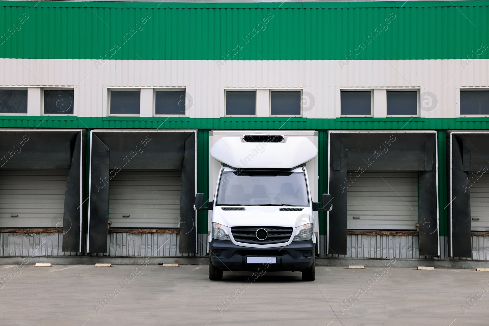 Image of Truck near loading dock of warehouse outdoors. Logistics center