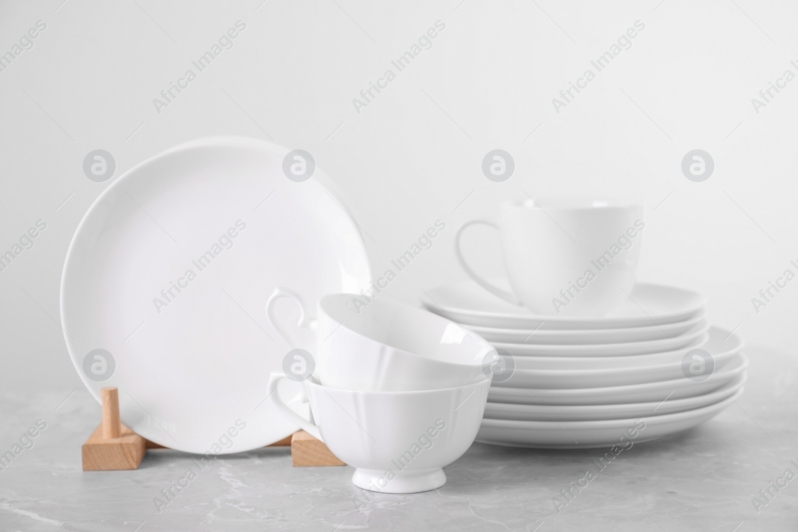 Photo of Set of clean tableware on light grey marble table