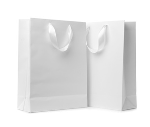 Paper shopping bags with ribbon handles on white background. Mockup for design