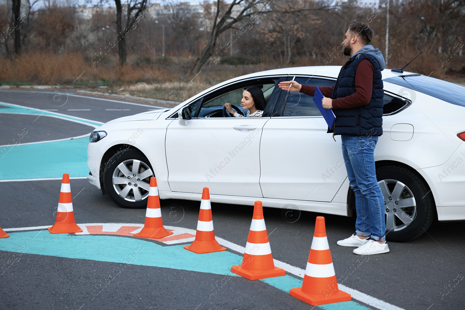 Photo of Instructor near car with his student during exam at driving school test track