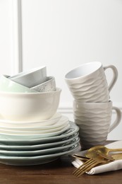 Beautiful ceramic dishware, cups and cutlery on wooden table