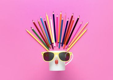 Flat lay composition with colorful pencils and cup on pink background