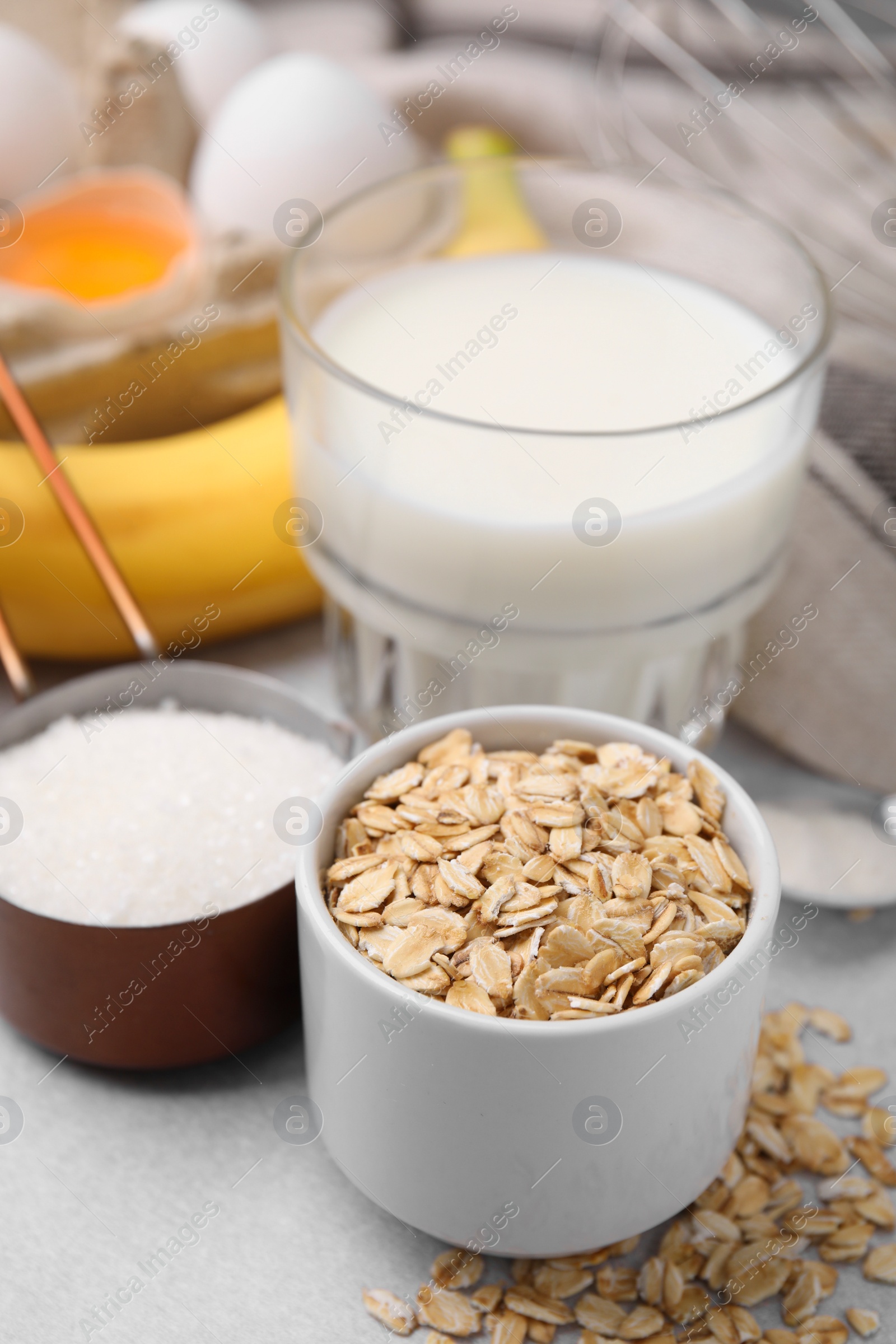 Photo of Different ingredients for cooking tasty oatmeal pancakes on grey table