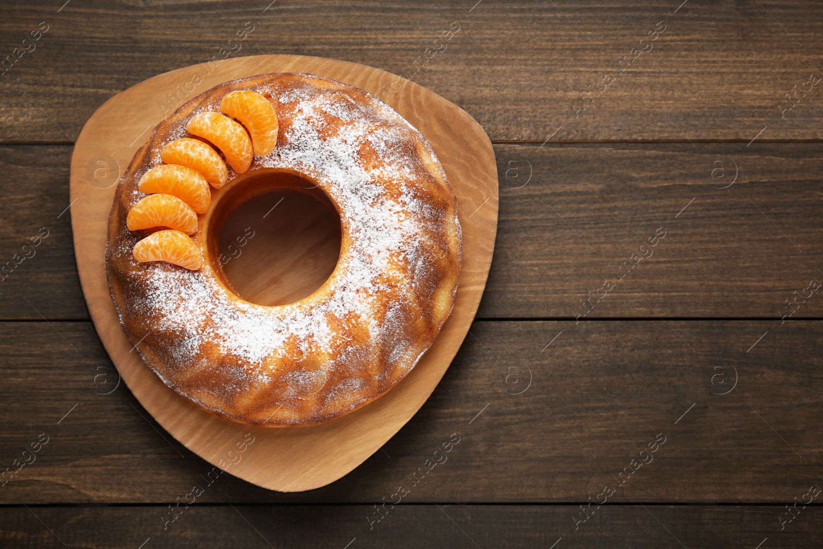 Photo of Homemade yogurt cake with tangerines and powdered sugar on wooden table, top view. Space for text