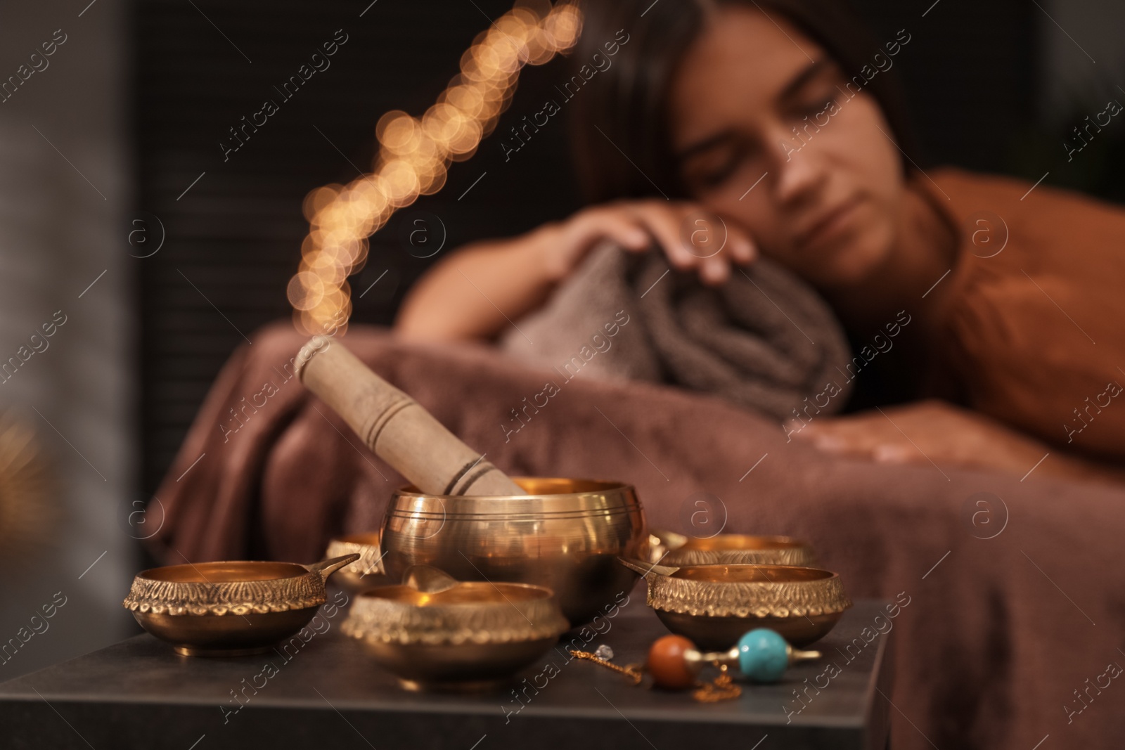 Photo of Woman at healing session in dark room, focus on singing bowl