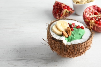 Yummy spirulina smoothie in coconut and pomegranate on wooden background. Space for text