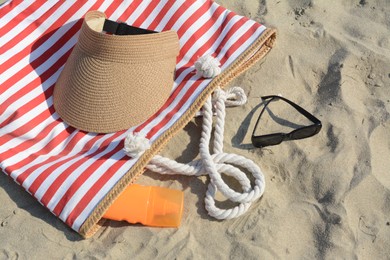 Stylish striped bag with beach accessories on sand