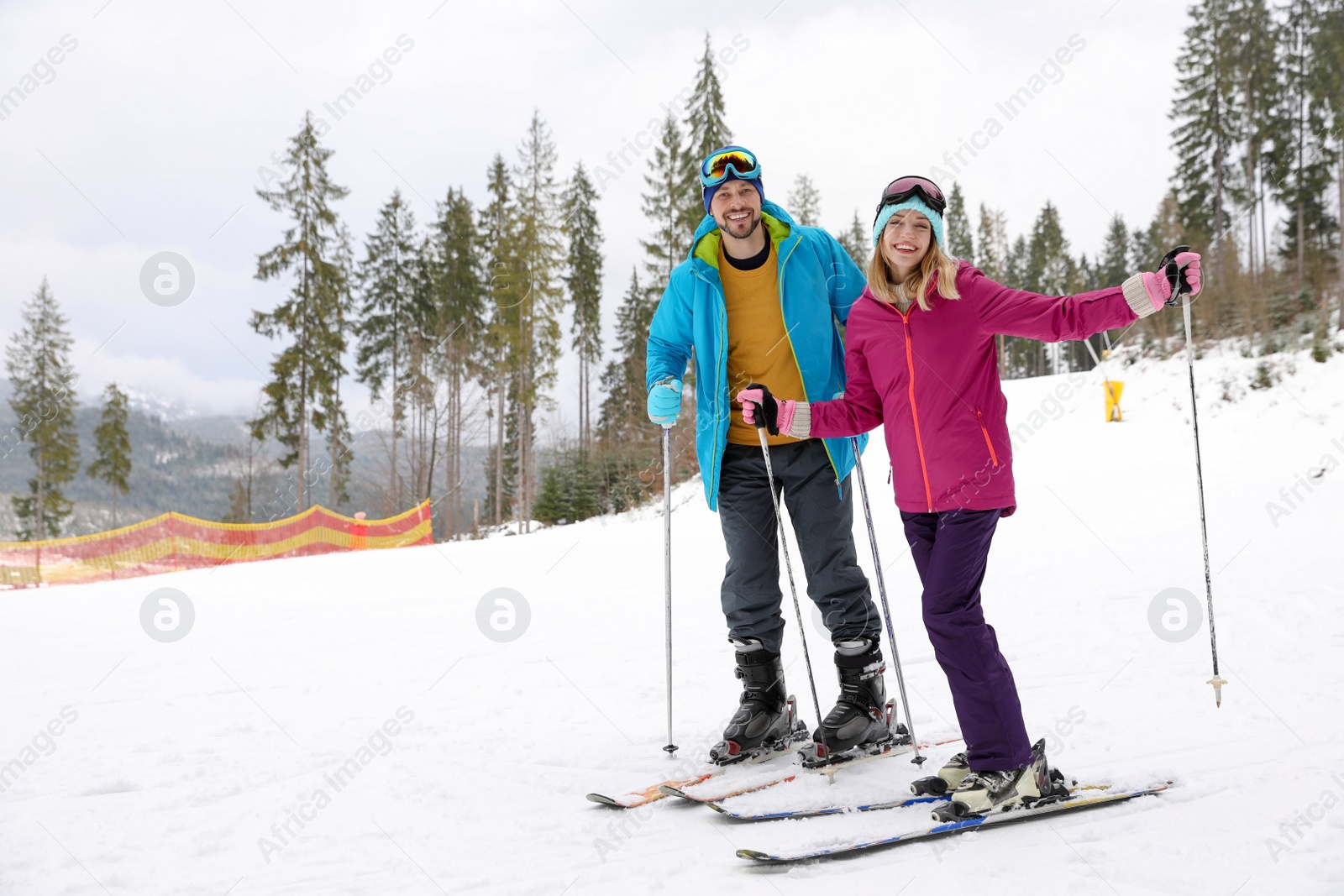 Photo of Couple of skiers on slope at resort. Winter vacation