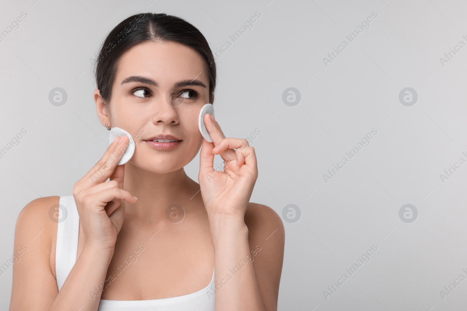 Photo of Young woman with cotton pads on light grey background. Space for text