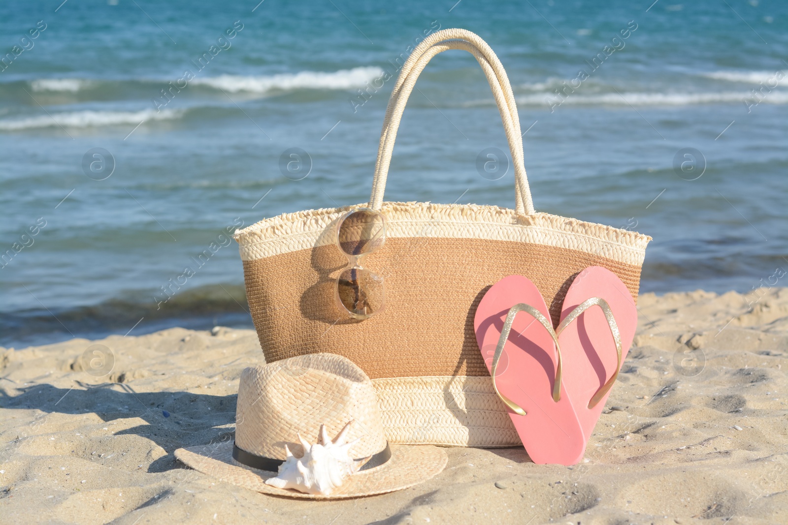 Photo of Stylish bag and other beach accessories near sea on sunny day