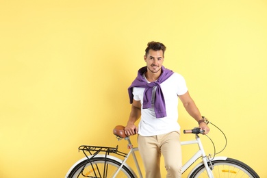 Photo of Handsome young hipster man with bicycle on yellow background