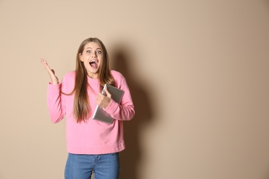 Emotional young woman with tablet celebrating victory on color background. Space for text