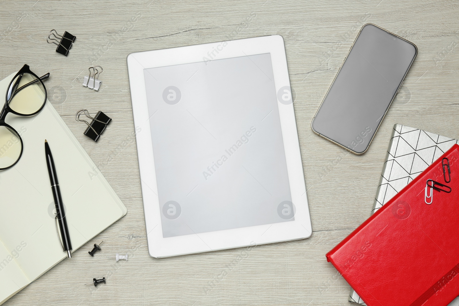Photo of Flat lay composition with tablet, smartphone and stationery on white wooden table. E-learning concept