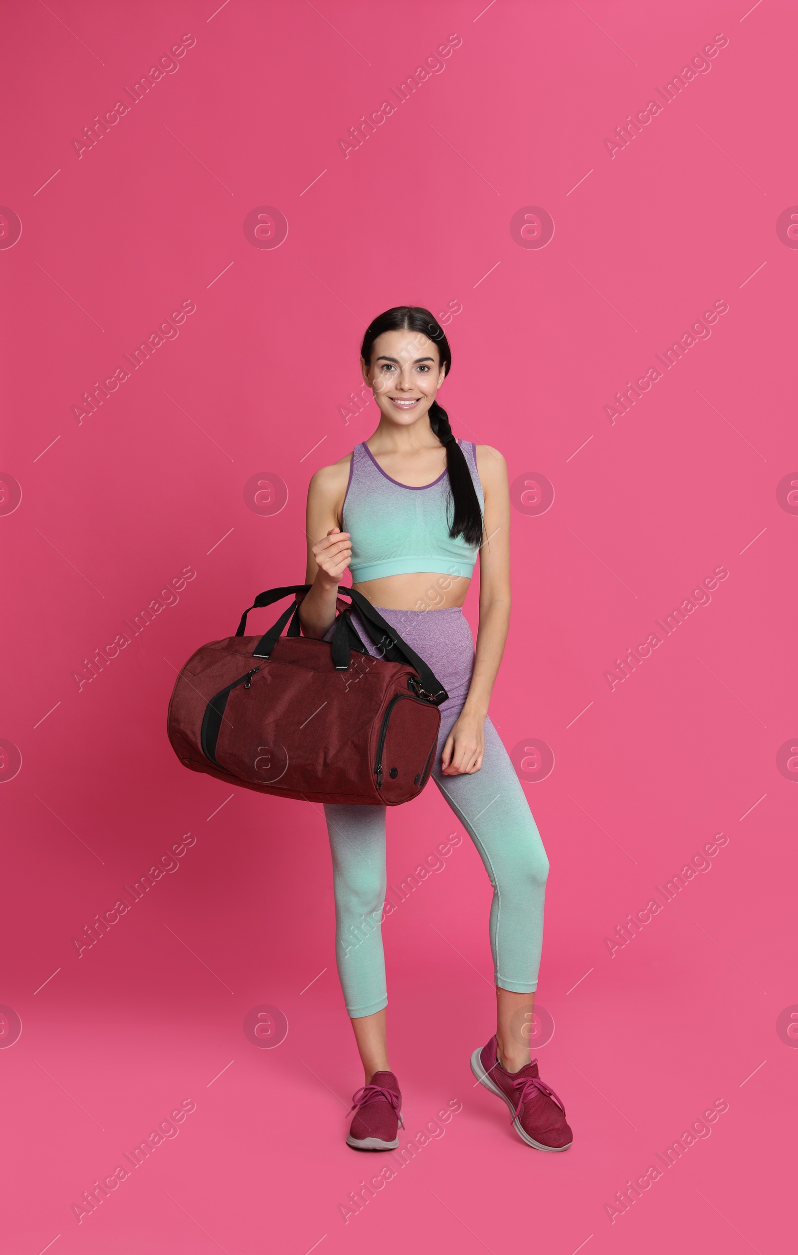 Photo of Beautiful woman with sports bag on pink background