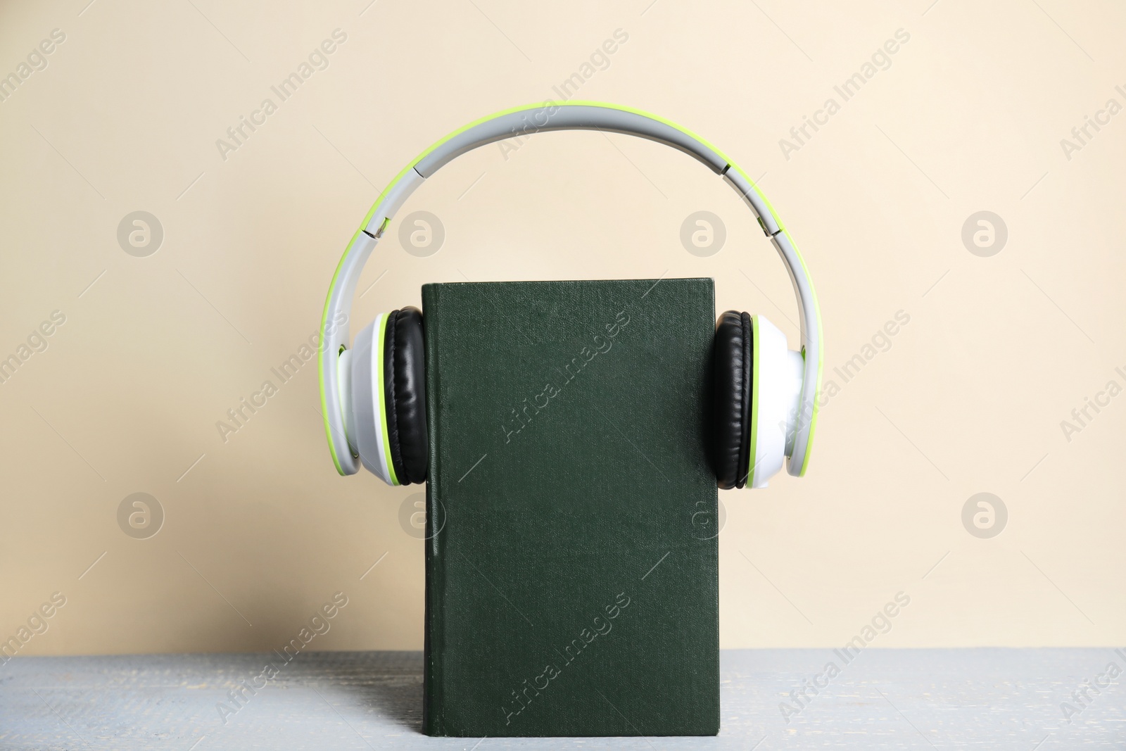 Photo of Book and modern headphones on grey wooden table