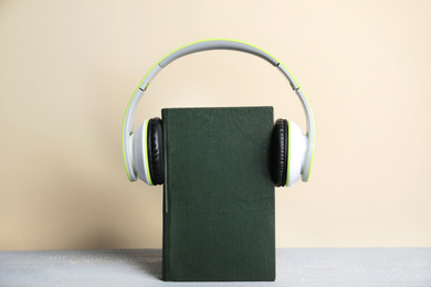 Book and modern headphones on grey wooden table