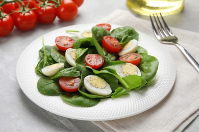 Photo of Delicious salad with boiled eggs, tomatoes and spinach on light grey table, closeup