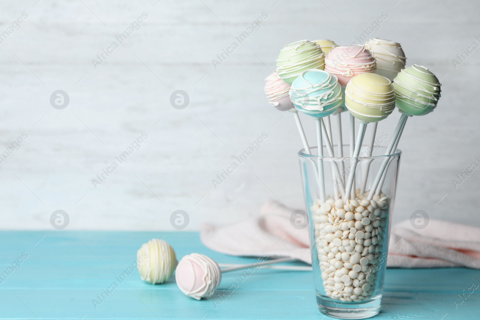 Photo of Sweet cake pops on light blue wooden table against white background. Space for text