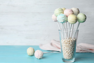 Sweet cake pops on light blue wooden table against white background. Space for text