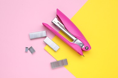 Photo of New bright stapler with staples on color background, fat lay. School stationery