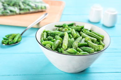 Photo of Frozen cut green beans on light blue wooden table, closeup. Vegetable preservation