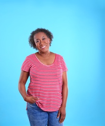 Portrait of happy African-American woman on light blue background