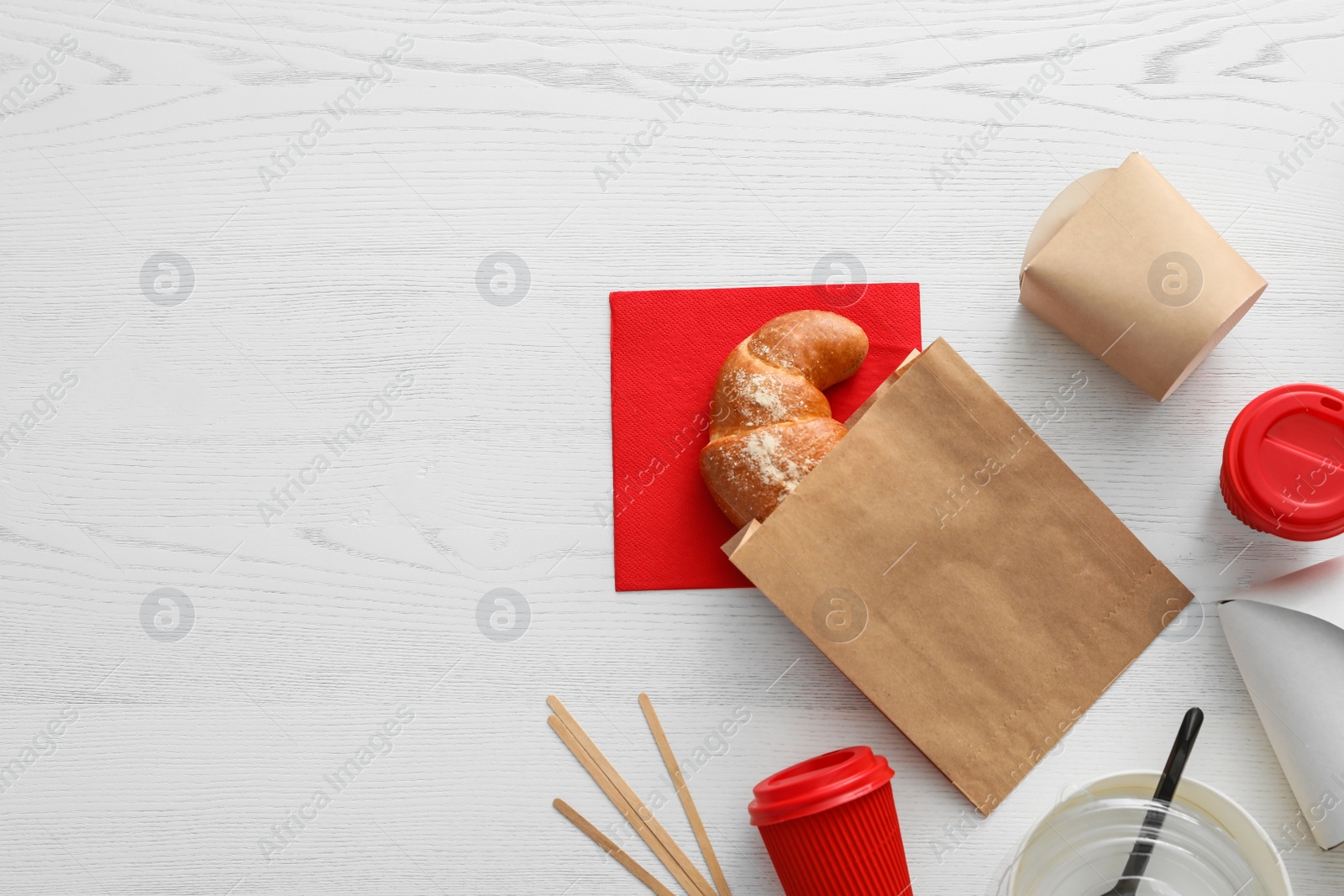 Photo of Flat lay composition with paper bag and different takeaway items on wooden background. Space for design