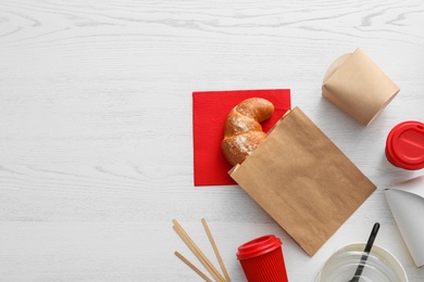 Photo of Flat lay composition with paper bag and different takeaway items on wooden background. Space for design