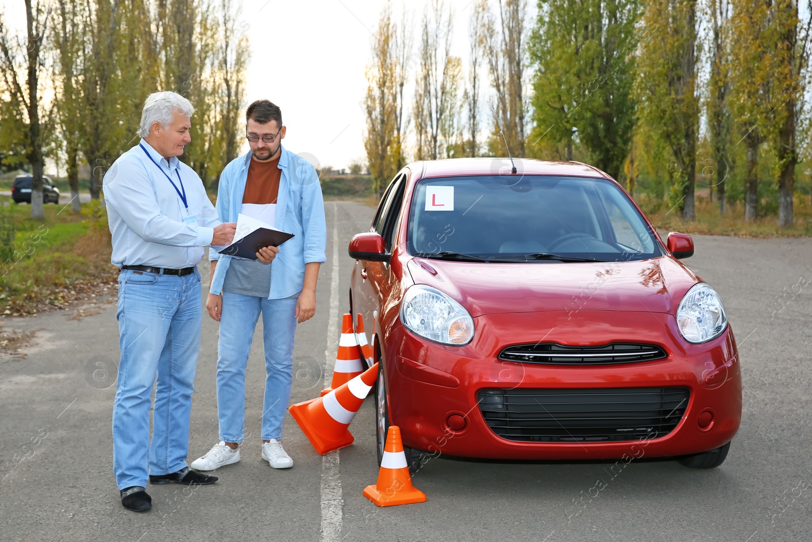 Photo of Senior instructor and man near car outdoors. Passing driving license exam