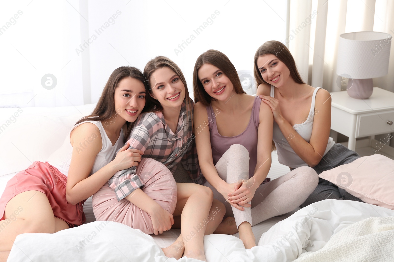 Photo of Beautiful young ladies on bed at pamper party. Woman's Day