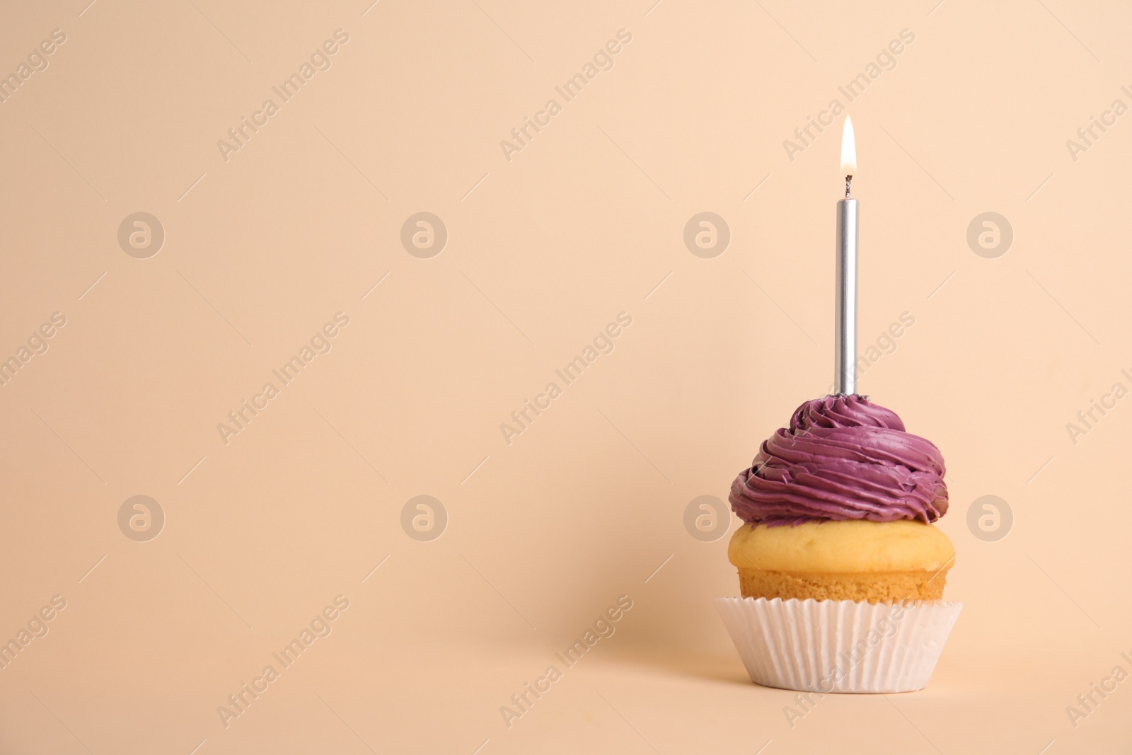 Photo of Birthday cupcake with candle on beige background, space for text