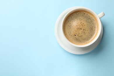 Aromatic coffee in cup on light blue background, top view. Space for text