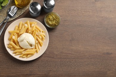 Photo of Plate of delicious pasta with burrata served on wooden table, flat lay. Space for text