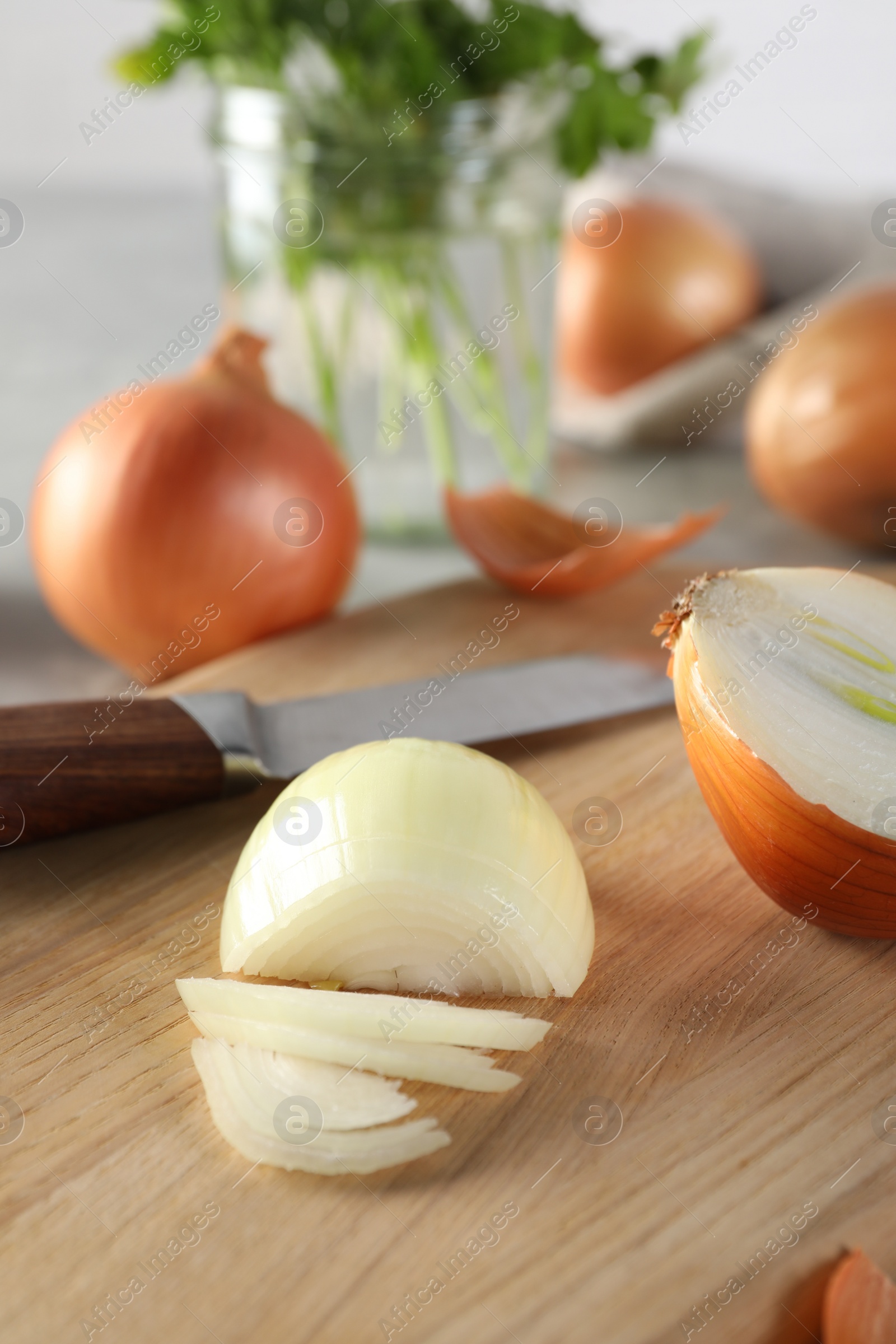 Photo of Whole and partially sliced onion on wooden table indoors