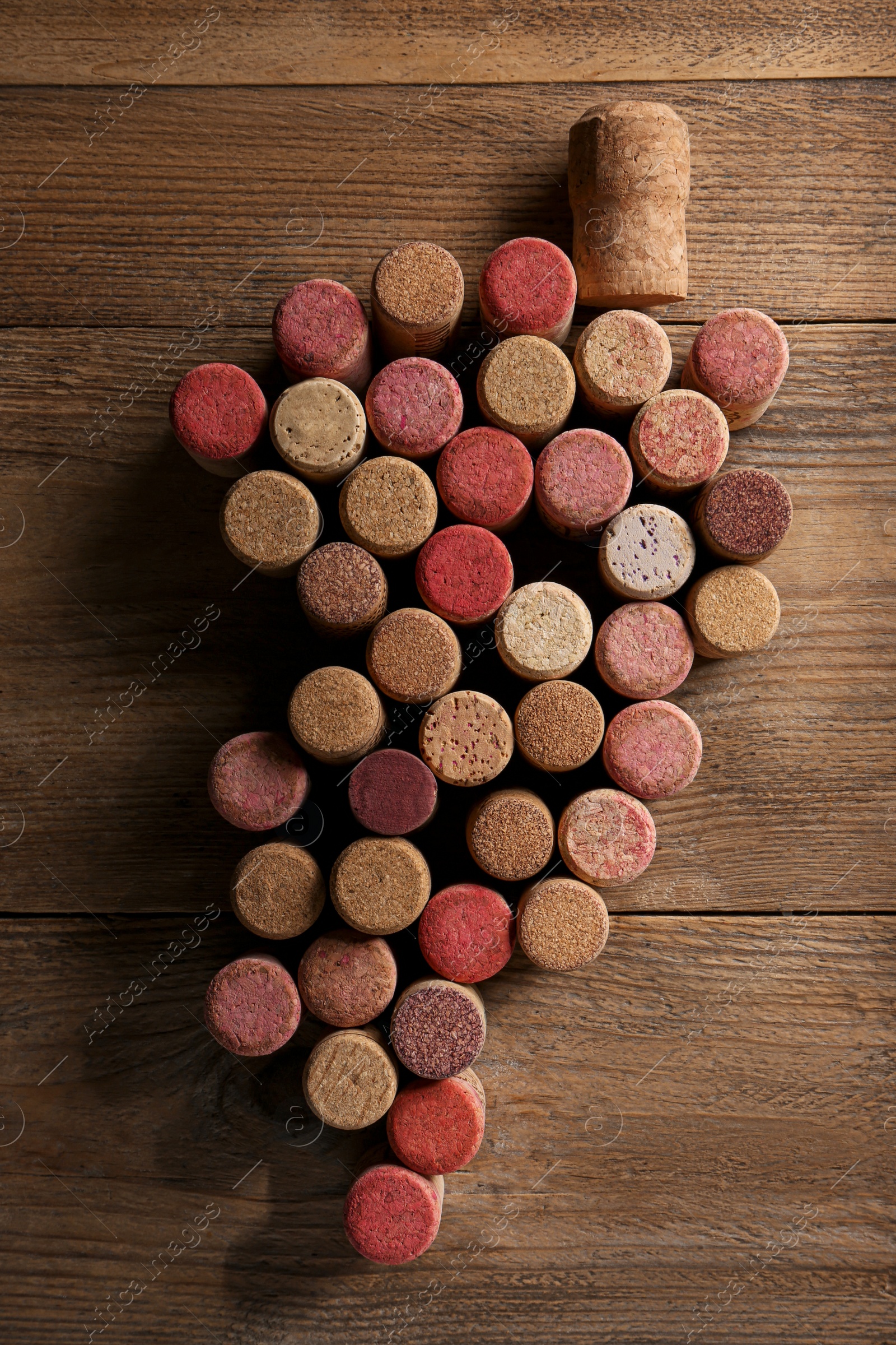 Photo of Grape made of wine bottle corks on wooden table, top view