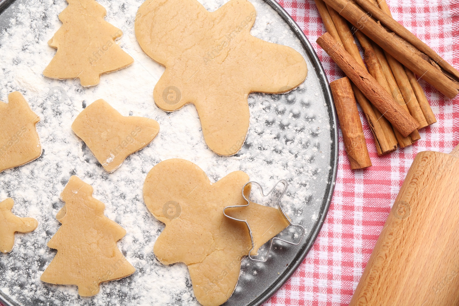 Photo of Raw Christmas cookies in different shapes and cinnamon sticks on table, flat lay