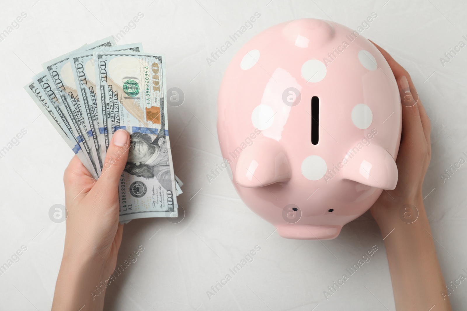 Photo of Woman with piggy bank and dollar banknotes at light table, top view. Money savings