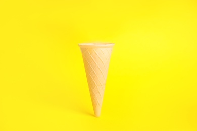 Photo of Empty wafer ice cream cone on yellow background