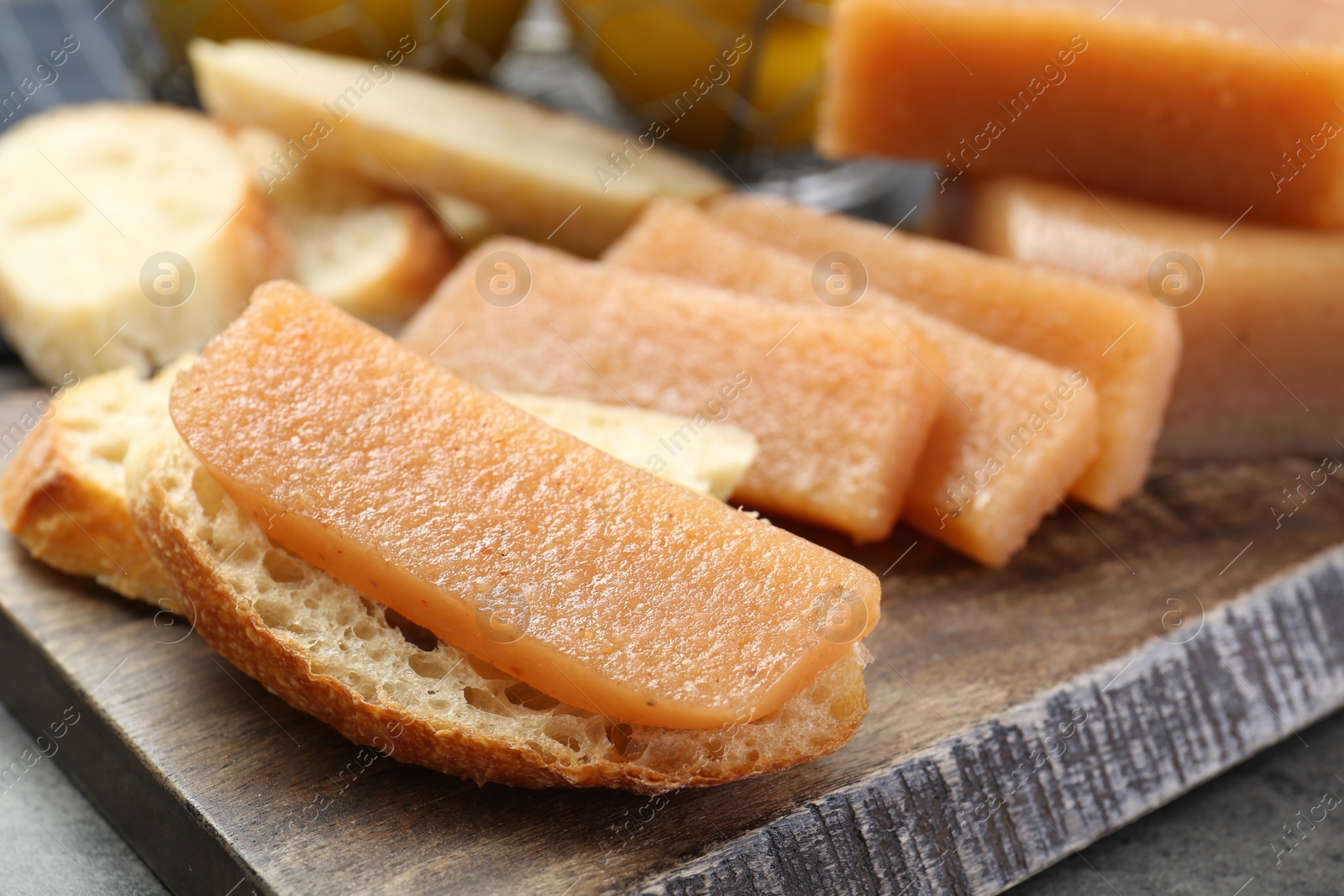 Photo of Tasty sweet quince paste and bread on grey table, closeup