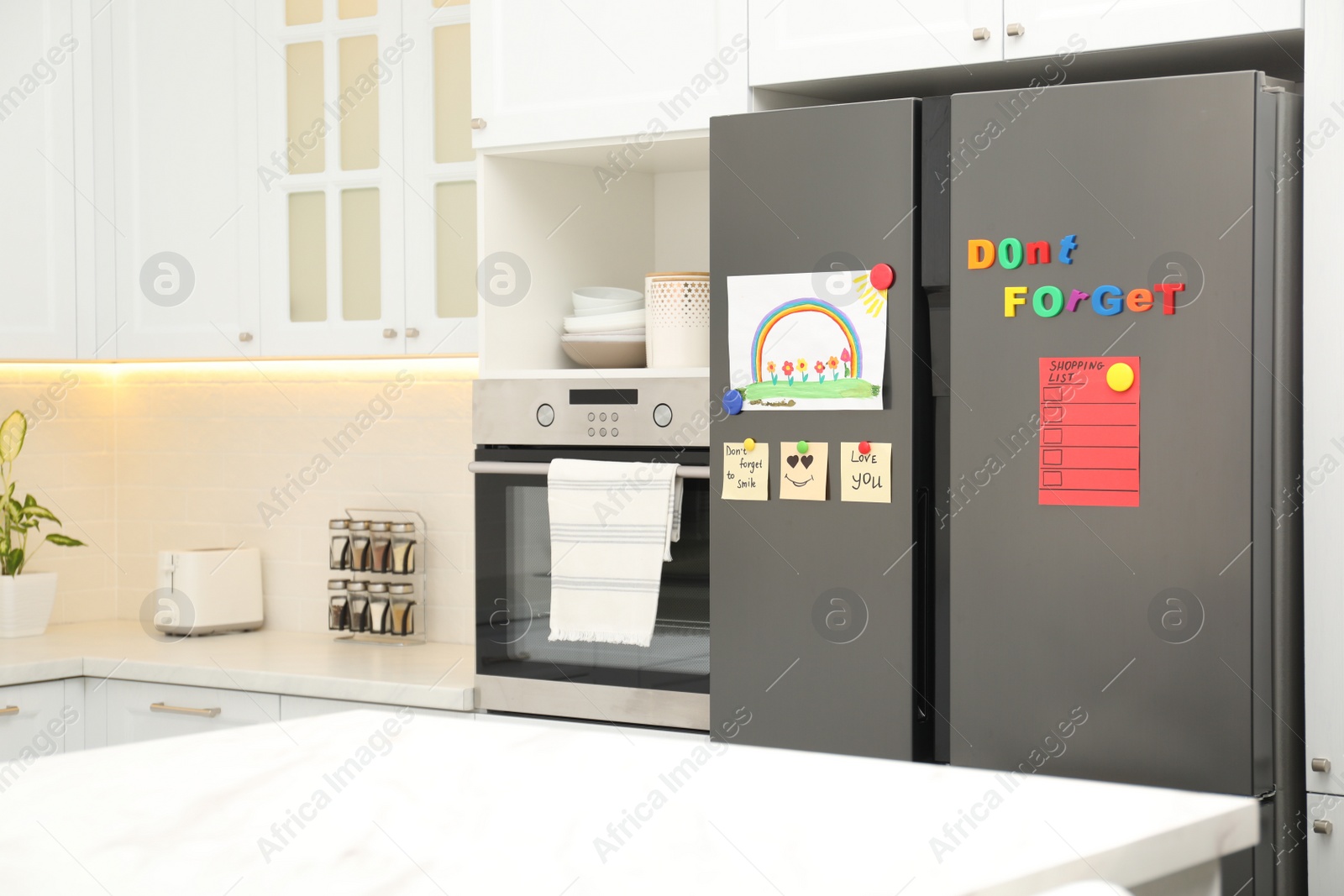 Photo of Modern refrigerator with child's drawing, notes and magnets in kitchen. Space for text