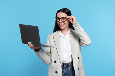 Photo of Happy woman with laptop on light blue background