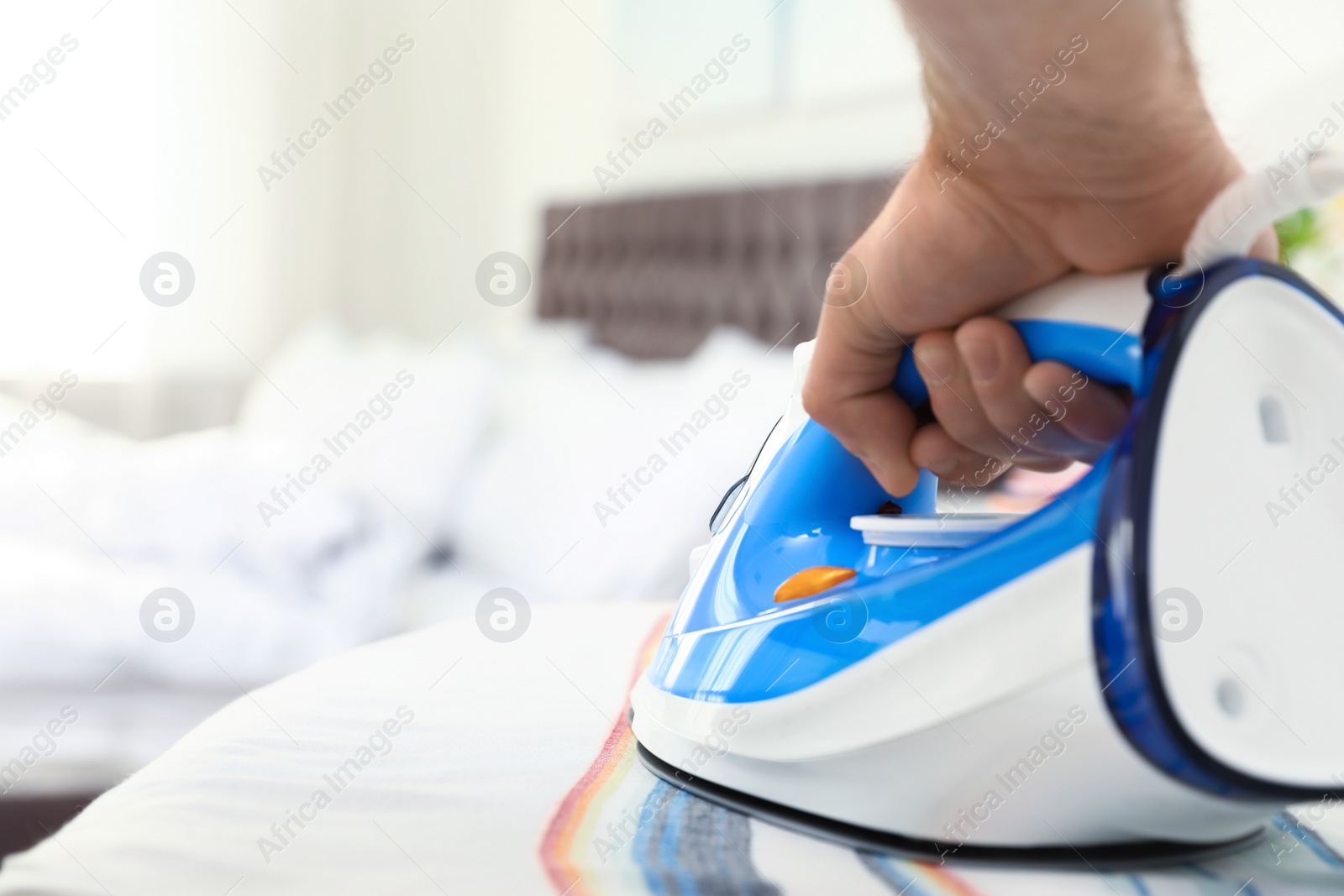 Photo of Man ironing clothes on board indoors, space for text. Household chores