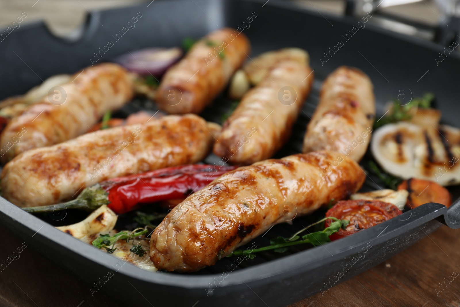 Photo of Tasty fresh grilled sausages with vegetables on wooden table, closeup