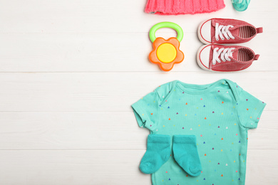 Photo of Flat lay composition with child's clothes and booties on white wooden table, space for text