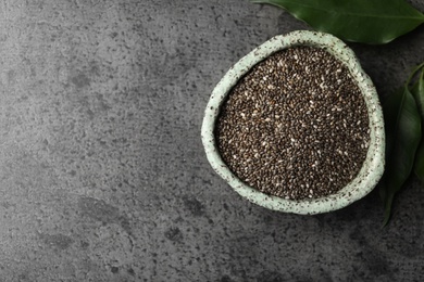 Photo of Bowl with chia seeds and leaves on grey table, flat lay. Space for text