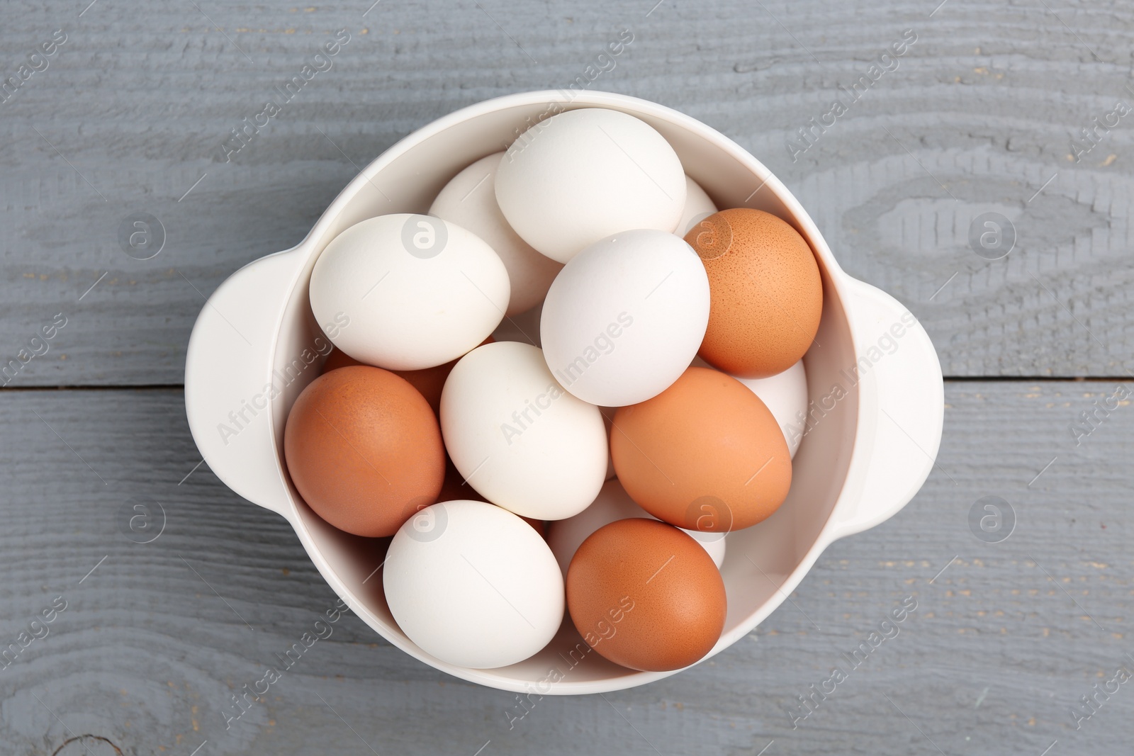 Photo of Unpeeled boiled eggs in saucepan on grey wooden table, top view