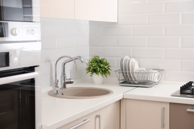 Photo of Clean dishes on counter near kitchen sink indoors