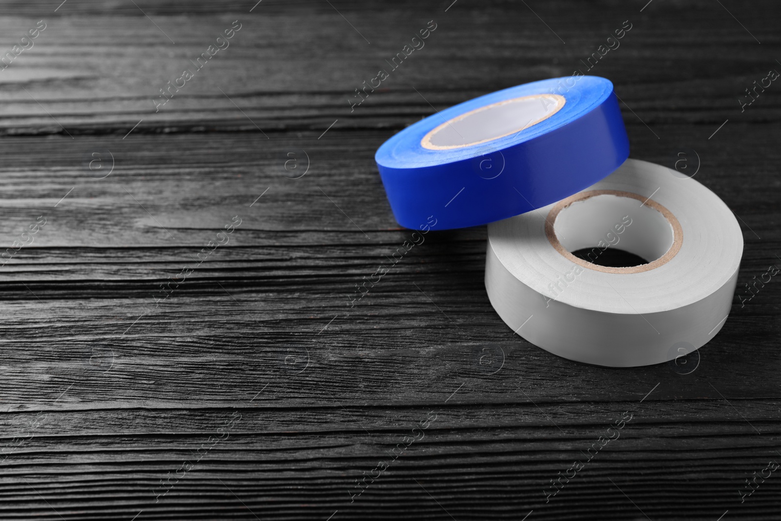 Photo of Colorful insulating tapes on black wooden table. Space for text