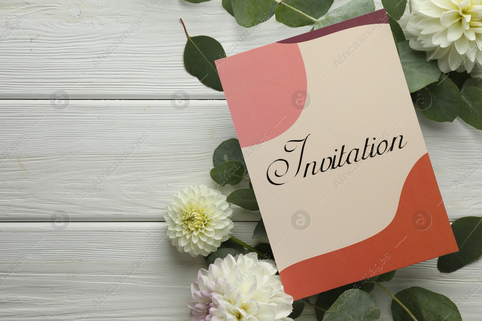 Photo of Card with word Invitation and beautiful flowers on white wooden background, flat lay. Space for text