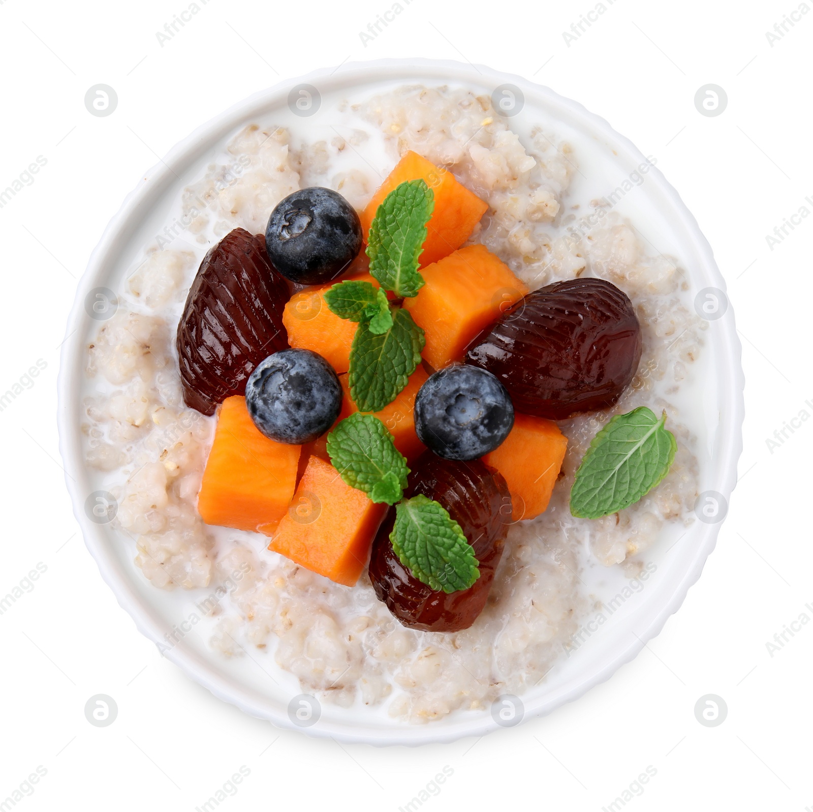 Photo of Delicious barley porridge with blueberries, pumpkin, dates and mint in bowl isolated on white, top view